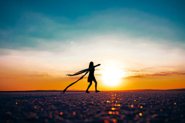 Silhouette of a sad woman holding heart shaped balloon  at the sunset.