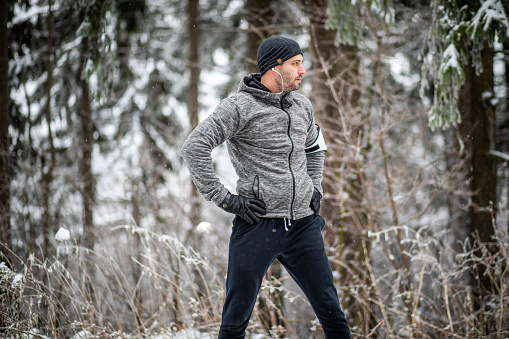 One man, an adult man is exercising in the snowy forest in the fresh air, he leads a healthy lifestyle, he is dressed in sports clothes