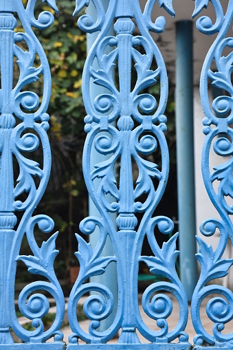 detail of a wall iron door. Blue patterned iron garden railings of an old house