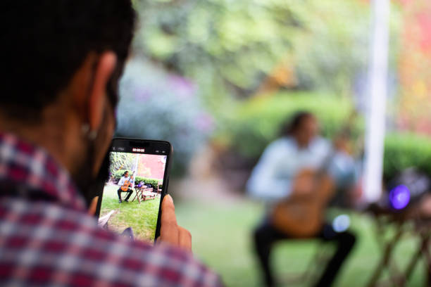 istock latin man recording with a smartphone a classical guitarrist guitar player playing spanish guitar in a private event party in a garden 1449913705
