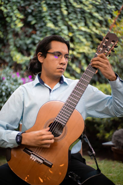istock young hispanic man classical guitar player playing spanish classical music in a concert in a garden 1449913716