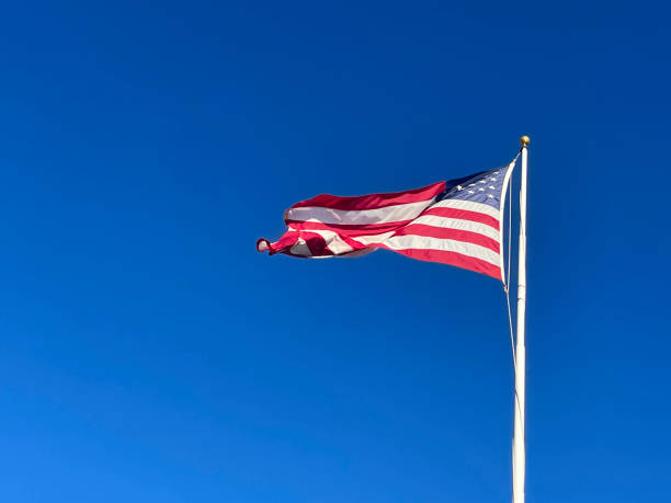 istock American flag blowing in the wind on the blue sky background 1449942377
