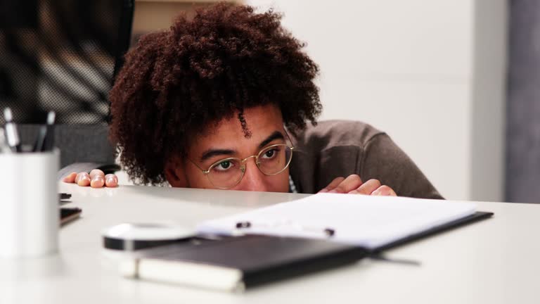 Scared Man Hiding Behind Office Desk