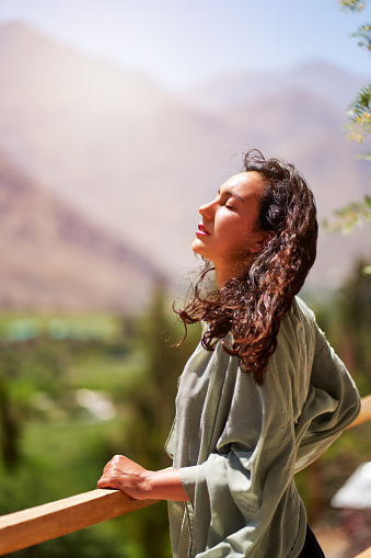 Young latin woman with eyes closed and head raised enjoying the sun and the breeze in the Valle del Elqui, Paihuano.