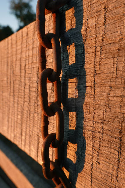 A chain hangs over a fence at a riding stable in the afternoon light.