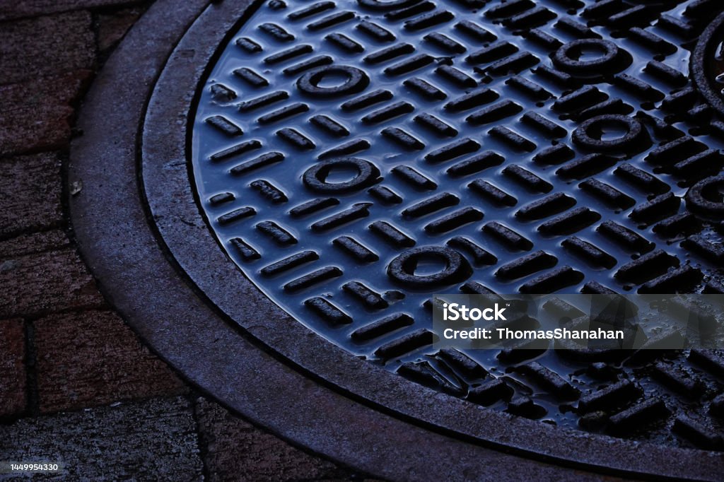 Water filled Manhole cover A abstract design emerges after a rainstorm and a city manhole cover. Manhole Stock Photo