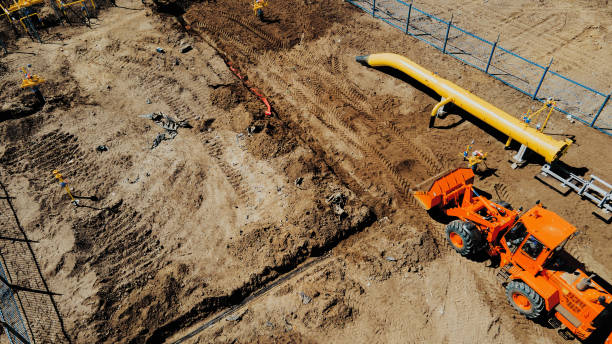 istock Aerial view excavator and construction workers working on construction site in open field. Pipe laying in trench for gasification. Top point of shooting. Repair and restoration of natural gas supply. 1449969714