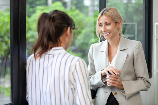 istock Two businesswoman colleagues talking at work share ideas in office, take a break from work and drink coffee. 1449970223