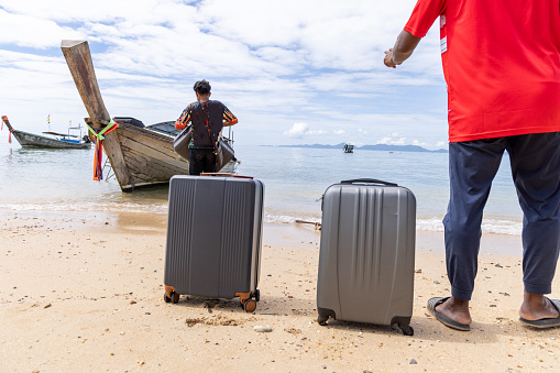 Two Thai men helping to carry baggages to the boat in a bay in Southern Thailand