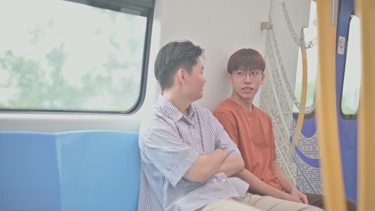 2 Generation Z Asian Chinese Teenage boy looking at smartphone in subway train