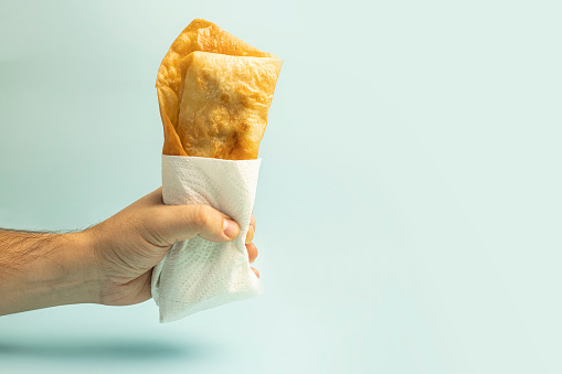 shawarma in a male hand blue background. copy space