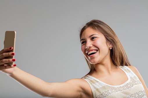 beautiful young woman gleefully watches the screen or takes selfies at the moment in her life when she is more beautiful than she will ever be