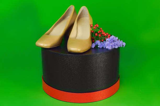 Beautiful female cared feet with blue polished nails in green sandals isolated on green paper background.