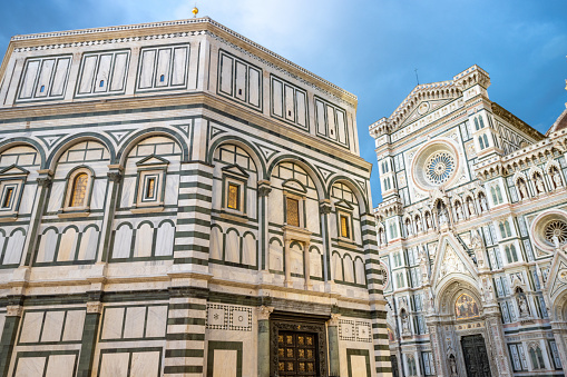 A sunny summer day in the Piazza del Duomo, with the Santa Maria Del Fiore cathedral and Giotto's Bell Tower in view as tourists enjoy the historic pedestrian zone of Florence, Italy.