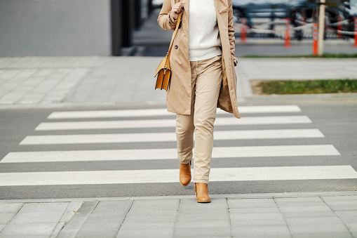 Cropped picture of a smart casual woman crossing a crosswalk downtown.