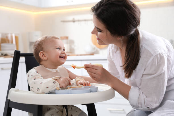 istock Mother feeding her cute little baby in kitchen 1450003571