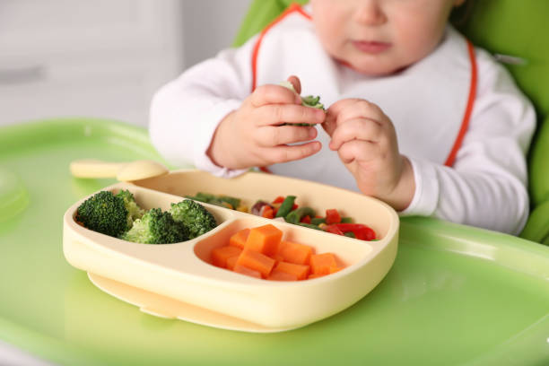 piccolo bambino che mangia cibo in seggiolone, primo piano - divided plate foto e immagini stock