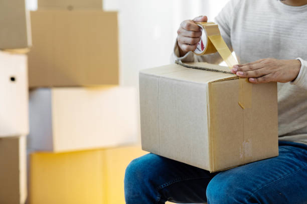 istock Man closing a cardboard box with tape at home 1450004640
