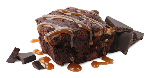 Delicious chocolate brownie with nuts and caramel sauce on white background