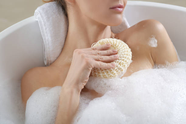 istock Woman with sponge taking bubble bath, closeup 1450005441