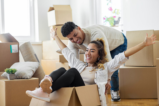Couple is having fun with cardboard boxes in new house at moving day