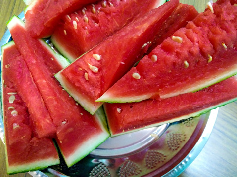 Penang, Malaysia. \n\nClose up of slices of red watermelon.\nServed on a stainless steel plate. Watermelon is non-seedless.