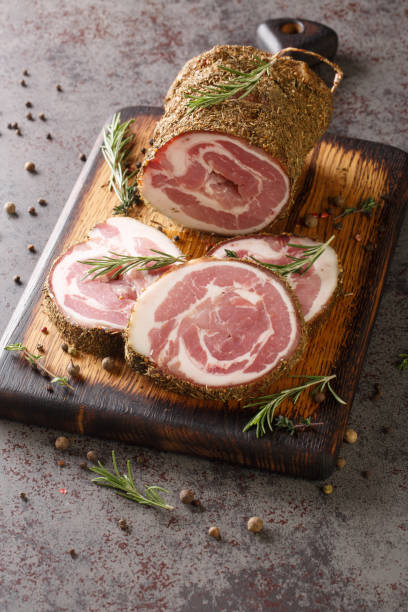 pork belly roll jerky in spices and herbs close-up on a wooden board. vertical - pancetta imagens e fotografias de stock