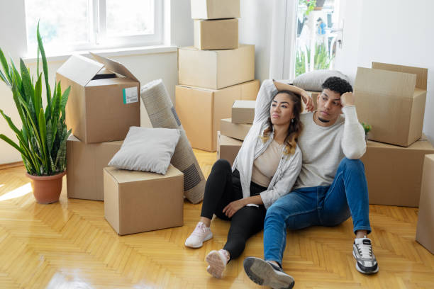 istock Unhappy couple sitting on floor with cardboard boxes, eviction 1450009690