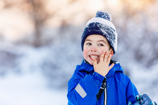 portrait of cute little boy applying cold cream to face outdoors. Winter skin protection concept