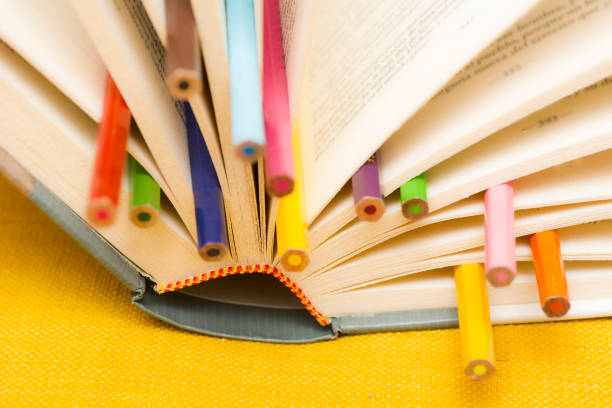 istock Open book wirh multicolored pencils on yellow background 1450011126