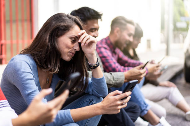 istock Pensive friends group using smartphone sitting at university college backyard - Young people addicted by mobile smart phone - Technology sad life concept with always connected students - Vivid filter 1450013644