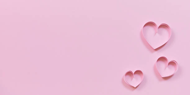 istock pink paper hearts on colored wallpaper for valentines day 1450014323