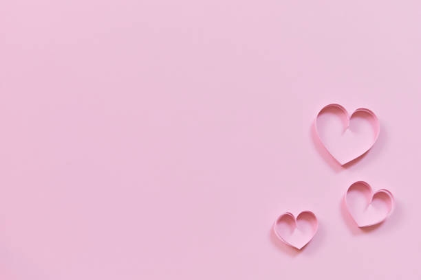 istock pink paper hearts on colored wallpaper for valentines day 1450014352