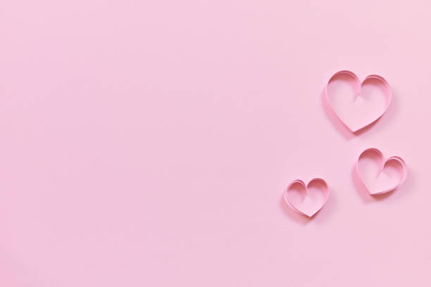 istock pink paper hearts on colored wallpaper for valentines day 1450014362