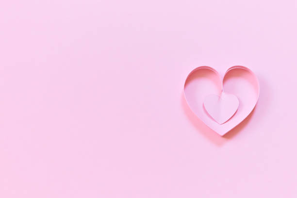 istock pink paper hearts on colored wallpaper for valentines day 1450014364