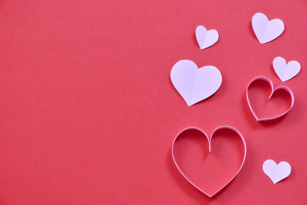 istock pink paper hearts on colored wallpaper for valentines day 1450014384