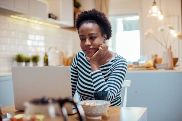 istock Young adult woman using a laptop while having breakfast 1450017606