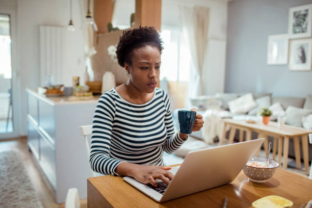 istock Young adult woman using a laptop while having breakfast 1450018186