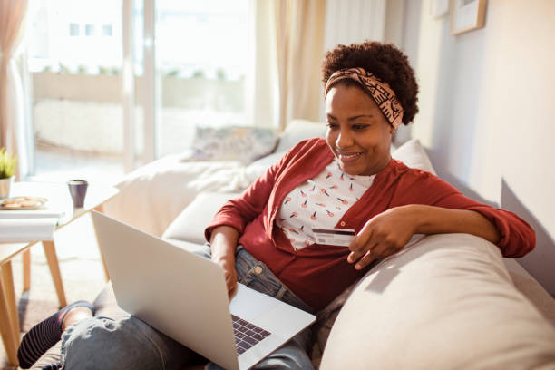 Young adult woman online shopping on her laptop Close up of a young adult woman using her laptop to online shop home shopping stock pictures, royalty-free photos & images