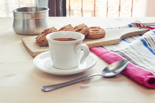 Close up view coffee break concept, with coffee cup, spoon, kitchen placemat, brown sugar and biscuits on a wooden table