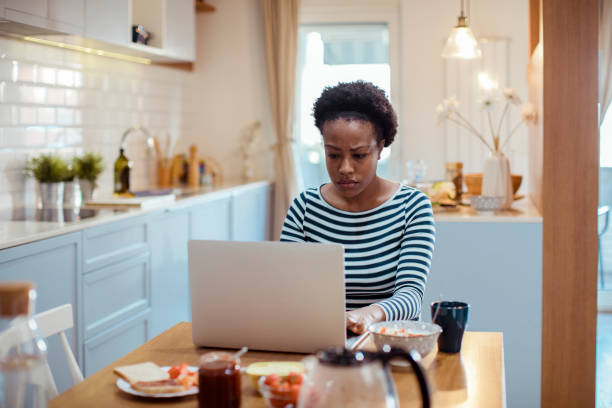 istock Young adult woman using a laptop while having breakfast 1450019900