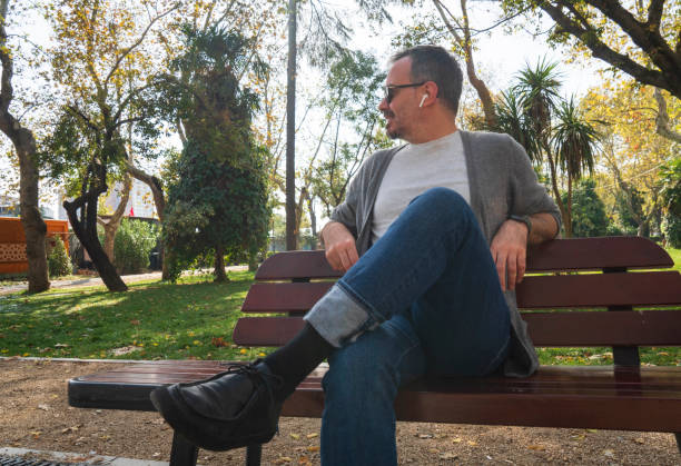 man relaxing sitting on a bench in a park