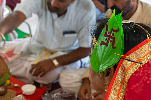 Mumbai, India - 07 December 2022, A leaf(paan) on the head of an Indian hindu woman during her marriage. Phere, bidai, haldi, mehendi, baraat, festival, ritual, marwari, rajputi, rajasthani, pooja.