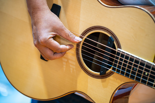 man's hand playing guitar