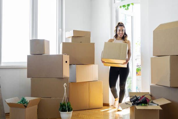 Woman carrying boxes into her new place Woman carrying boxes into her new place home ownership women stock pictures, royalty-free photos & images