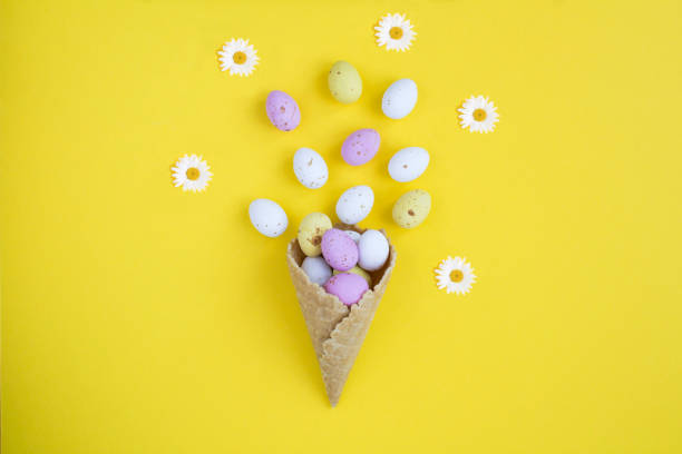 istock Ice cream cone with colored easter eggs on the yellow background. Top view. Copy space. 1450029510