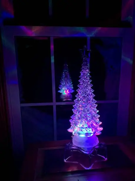 Water globe Christmas tree glows and is reflected in window