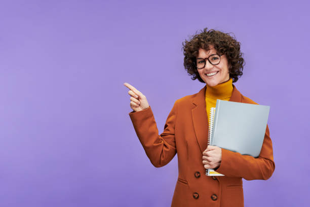 young cheerful teacher or economist with documents pointing at copyspace - concentration teacher business copy space imagens e fotografias de stock