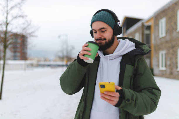 istock Handsome young man with a beard using his phone outdoors while wearing headphones 1450037226