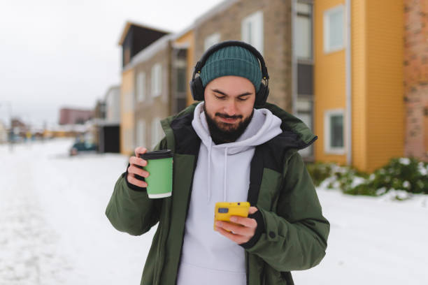 istock Handsome young man using his phone outdoors while wearing headphones 1450037281